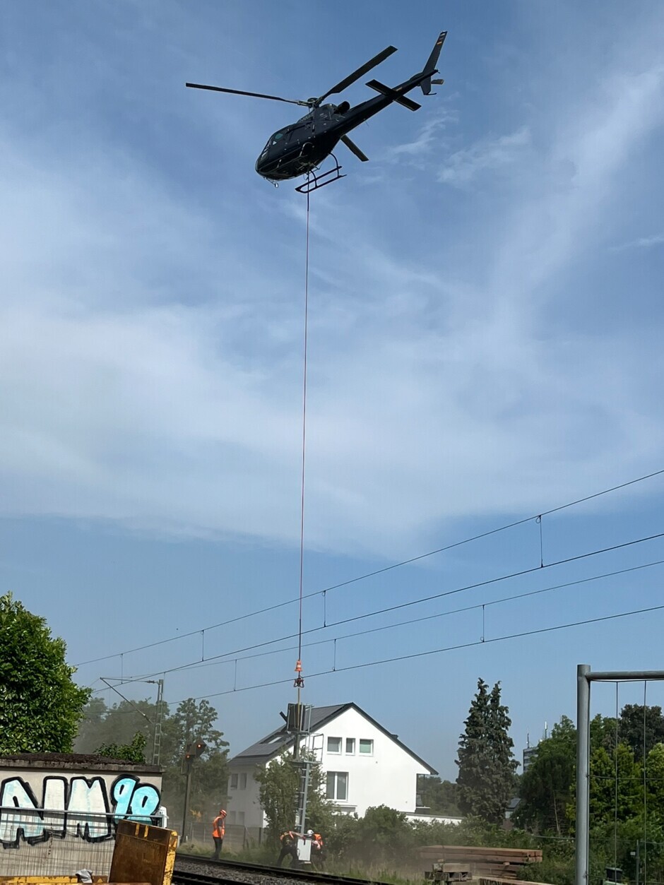 Für den Ausbau der S13 bringt ein Helikopter die neuen Signale an ihren Standort.